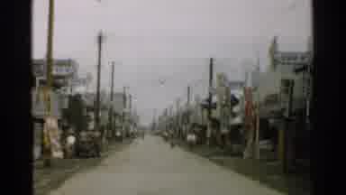 Japan (1952): Man Driving Truck Through Small Downtown Road Storefronts Signs