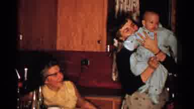 New Hampshire (1952): Woman Wearing Black Sweater Holds Baby Wearing Blue Snow