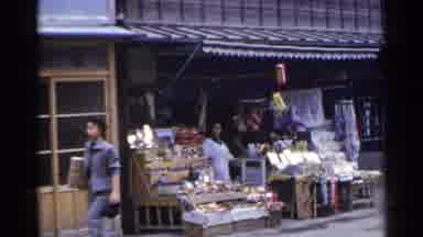 Japan (1953): Woman In White Stands In Her Open Air Stand As A Woman Passes Then