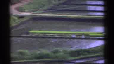 Japan (1953): Long Yellow Object During The Day With Grass And Reflective Water