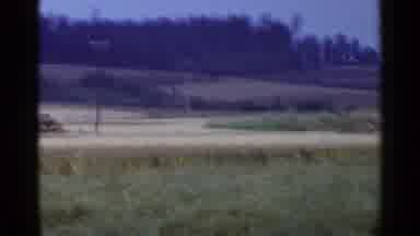 Japan-1953: A Grassy Field With Hills On The Horizon And Trees