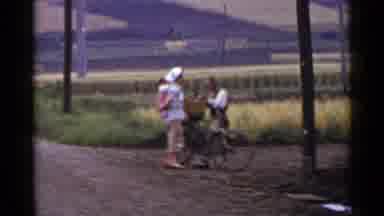 Japan (1953): A Woman Supports A Papoosed Child On Her Back While Speaking To A