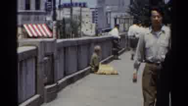 Japan (1953): People Go On Their Way And Ignore Peddler Seated On The Ground