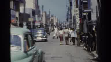 Japan (1953): A Busy City Street Lined With Stores Traffic And Pedestrians