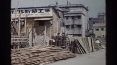 Japan (1953): Building Near Wood Pile Then Shot Of River With Ship And Traffic