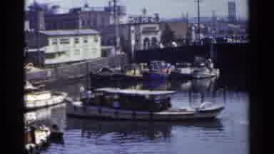 Japan (1953): A House Boat Driving In A Canal In A City While A Speed Boat Drives