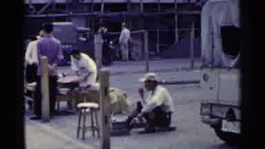 Japan (1953): A Man In A Hat Walks By A Busy Foreign Market
