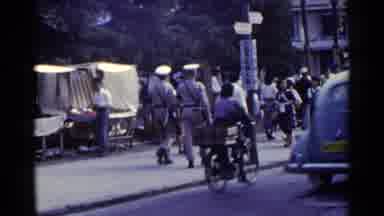 Japan (1953): Two Uniformed Men Walk Up Road Then Shoe Repairman Works On His