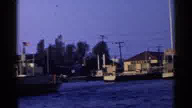 California-1955: A Vintage Boat Ride Past Riverside Homes and an American Flag