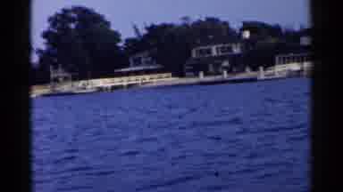 California (1955): Passing Moored White Sail Boat At Twilight Near An Urban Area