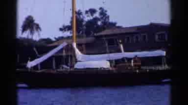 California (1955): A Boat Floats At Dock In Blue Water In Front Of A House