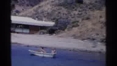 California (1955): Couple Rowing A Boat On An Island Near The Shore With A House