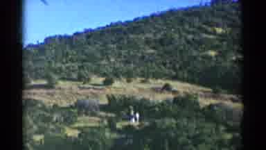 California (1955): Two People Walking On A Hill Covered With Trees
