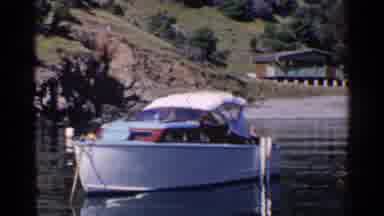California (1955): Parked And Lonely Boat On River Near Green Area With Tall House