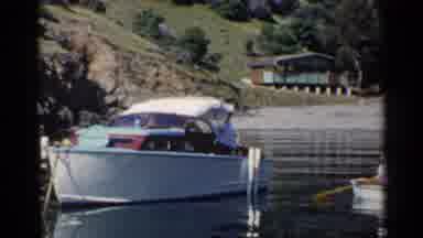 California (1955): Man Beside A Motorized Boat Rowing A Rowboat