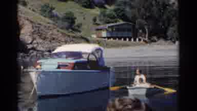California (1955): People Approaching To Lonely Boat On River Near Green Area With