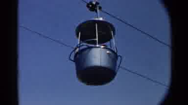 Disneyland-1959: Green Cable Car Cabins With Passengers in Blue Sky
