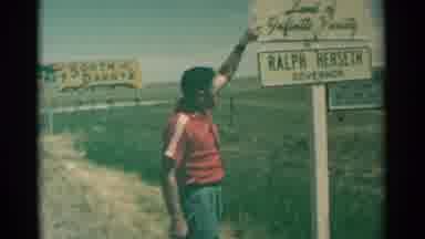 South Dakota (1959): Red Dressed Man Pointing Sign And Woman Taking A Photo At Him