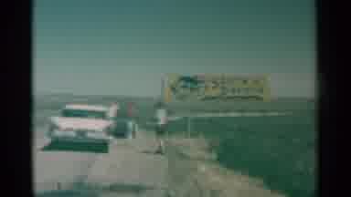 South Dakota (1959): People Standing On The Road With A Car In The Middle Of A