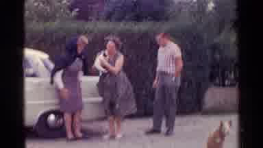 Germany (1961): A Man And Two Women Play With A White And Black Puppy Outside