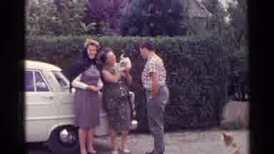 Germany (1961): A Woman Is Excited To Hold A White And Black Puppy While Standing