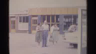 Germany (1961): People Standing In Front Of A Store And Next To A Car As A Lady