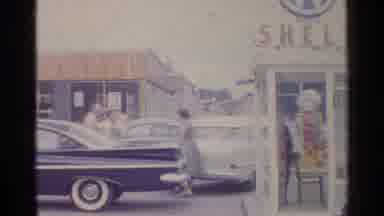 Germany (1961): On A Windy Day Two Women Talk In A Car Lot While Standing Outside