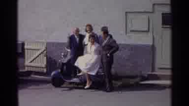 Germany (1961): Man Greets Wife Near A Vintage Scooter With Friends With Him
