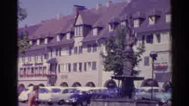 Switzerland (1961): People Coming Out And Going In Building With Lots Of Cars