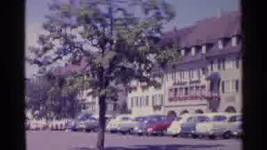Switzerland (1961): A Large Building With Several Cars Parked Out Along The Street