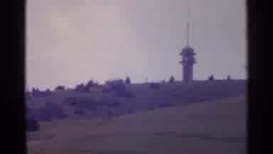 Switzerland (1961): Green Rolling Hills Next To A Tall Brown Tower Dotted By Many