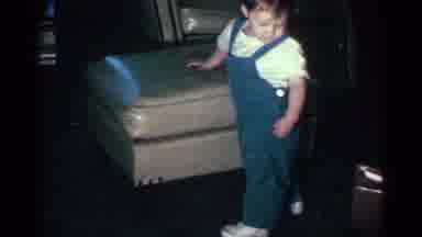 Kentucky USA (1963): A Toddler In Blue Overalls Stands Next To A Leather Ottoman