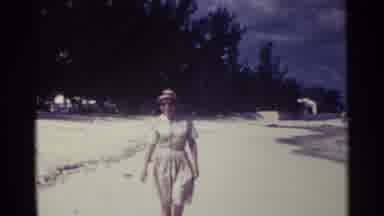 Nassau Bahamas (1963): A Woman Wearing A Hat And Glasses On The Beach Walking