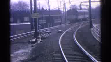 Ohio USA (1965): A Train Going Down The Tracks With A Metal Railing Hanging Above