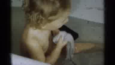 Michigan USA (1939): Toddler Washing In Filled Tub With Cloth Blue Eyes Looking At
