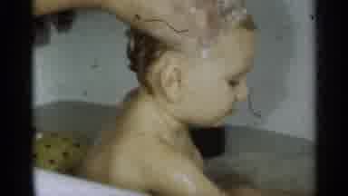 Michigan USA (1939): A Baby Sits In A Pool Of Water Playing While Getting Its Head