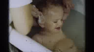 Michigan USA (1939): Baby Getting Washed In Bathtub Crying With Water In Eyes