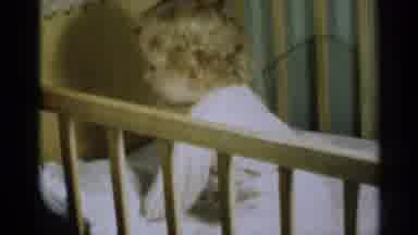 Michigan USA (1939): Baby In A Crib Playing With Her White Pillow