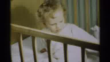 Michigan USA (1939): Little Child Dressed In White Pajamas Is Laying In A Crib