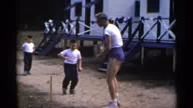 New York USA (1954): A Tall Man Picking Something Off The Ground With Small