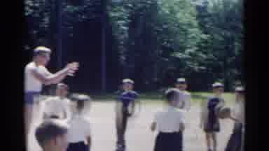 New York USA (1954): Men Tossing A Ball To Children And A A Totem Pole