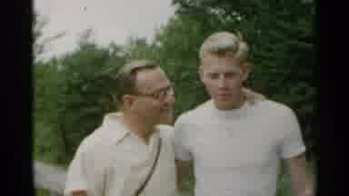 New York USA (1954): Couple Walking From Green Trees Waving At Camera On A Clear