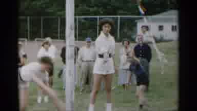 New York USA-1954: Boy Wearing Blue Shirt And Shorts Turns Cartwheel Next To Woman With Baton