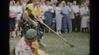 New York USA (1954): A Crowd Watches A Girl Dressed In A Clown Dress Chasing Two