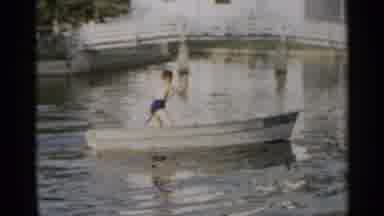 New York USA (1954): Two Young Boys Wearing Swimming Trunks Rowing A Boat Together