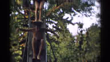 New York USA (1954): Young Man Sliding Down A Metal Slide At A Park Then Jumping