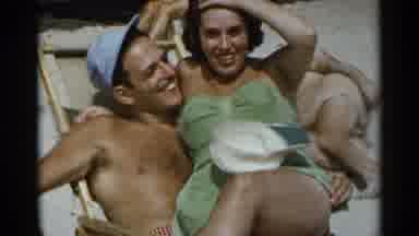 New York USA (1954): Couple Sit Together On Beach While Two Others Build Concrete