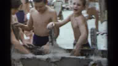 New York USA (1954): Several Children Laugh As They Bury Another Child In The Sand