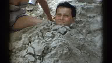 New York USA (1954): Young Boy Being Buried In The Sand By His Friends And Family