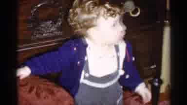 New York City (1955): Toddler Wearing Blue Sweater Holds Onto Brown Seat Cushion